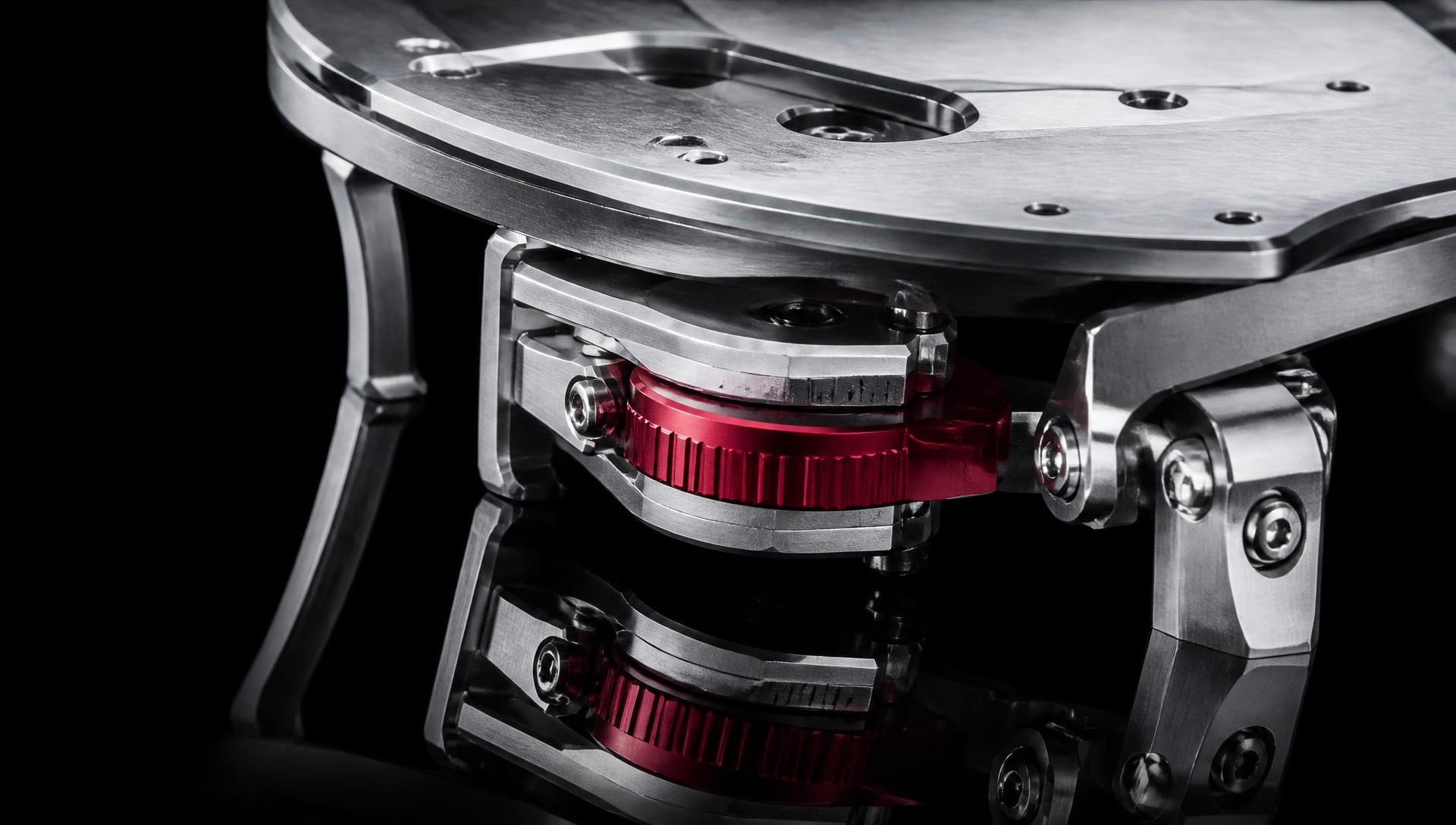 Macro of a machined aluminium mechanism with an oxide-red anodised part on black glass