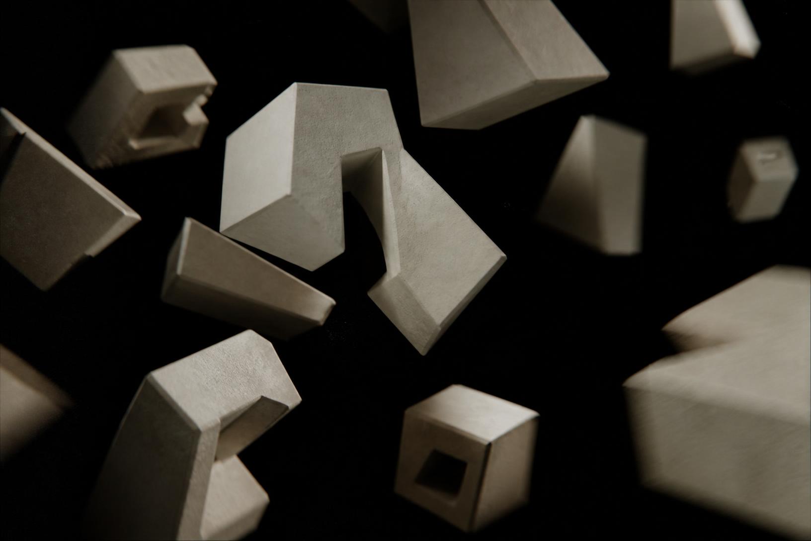 Bone-white letterform blocks tumbling with real weight